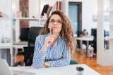 Striped-shirt person pondering email re-engagement strategy at their desk.