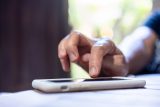 A hand touches a smartphone, ready to create shareable content on the screen.