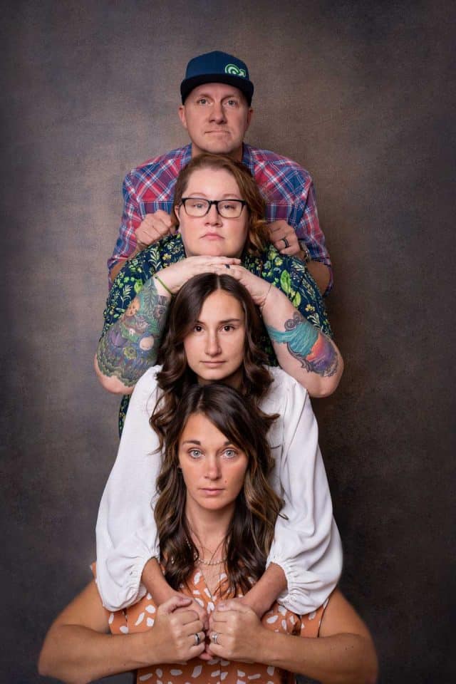 Four people stacked vertically, each leaning on the one below.