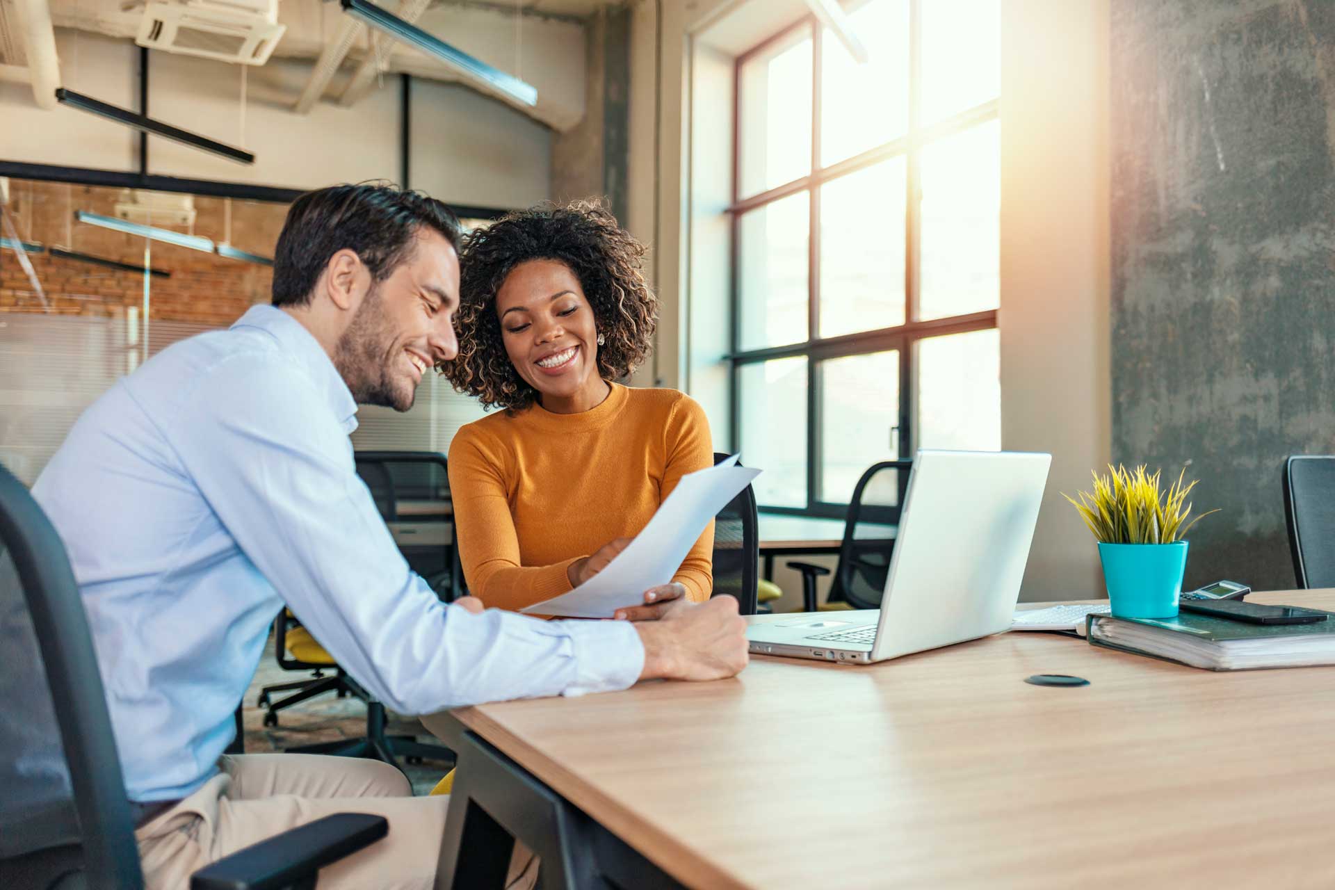 Two people reviewing a document together at an office table.