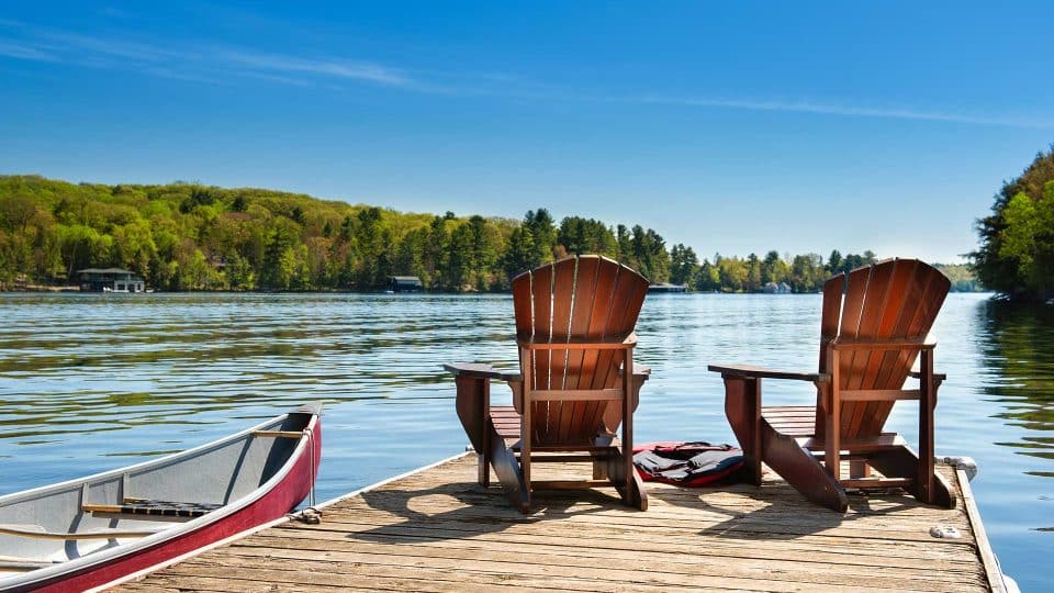 Two wooden chairs on a dock in Kosciusko County, overlooking a calm lake.