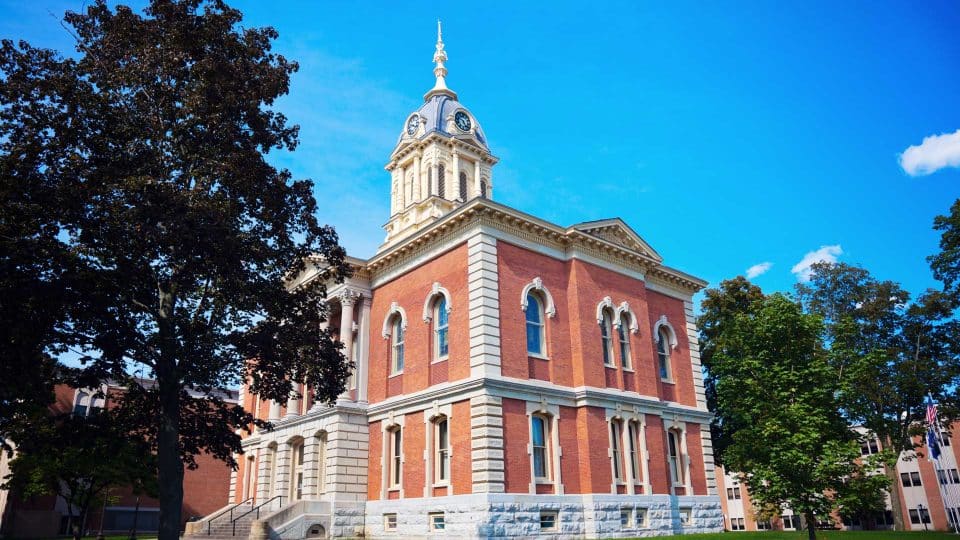 Plymouths historic red brick courthouse, clock tower amidst trees.