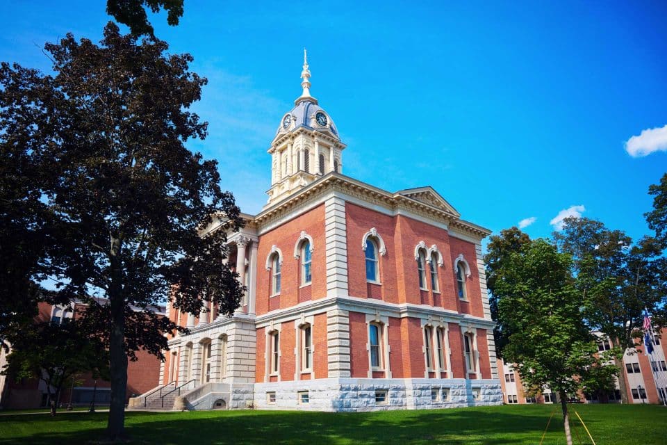 Plymouths historic red brick courthouse, clock tower amidst trees.
