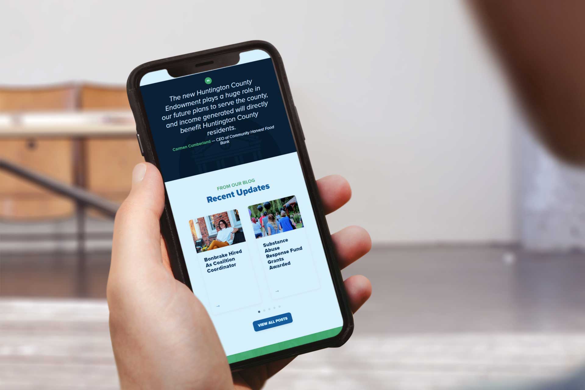 Person holding a smartphone showing the Community Foundation of Huntington County site.