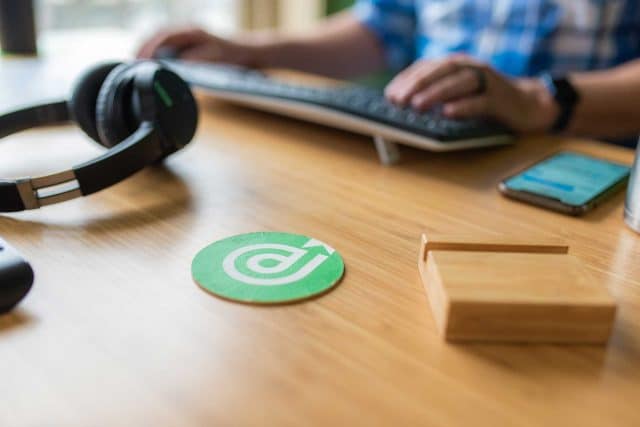 Person typing on keyboard with headphones, coaster, and brand consulting notes.
