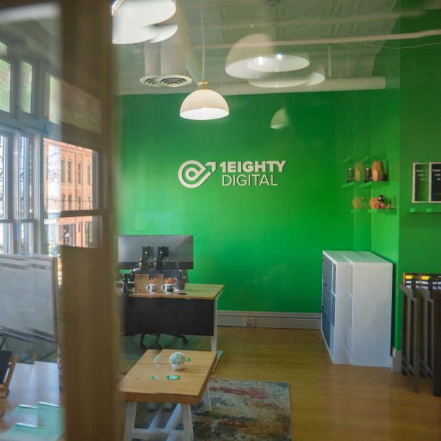 Office with green walls, 1Eight Digital logo, and contract web design stations.