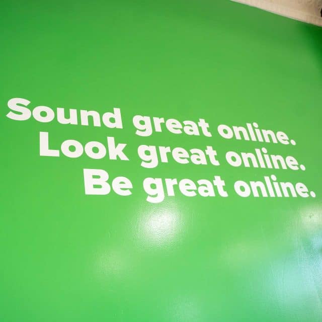 Green wall with: Sound, look, and be great online. Perfect social media management.