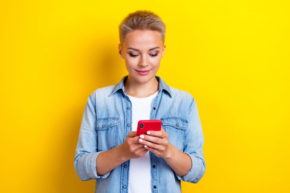 Person in denim shirt uses a red phone with Facebook analytics open.