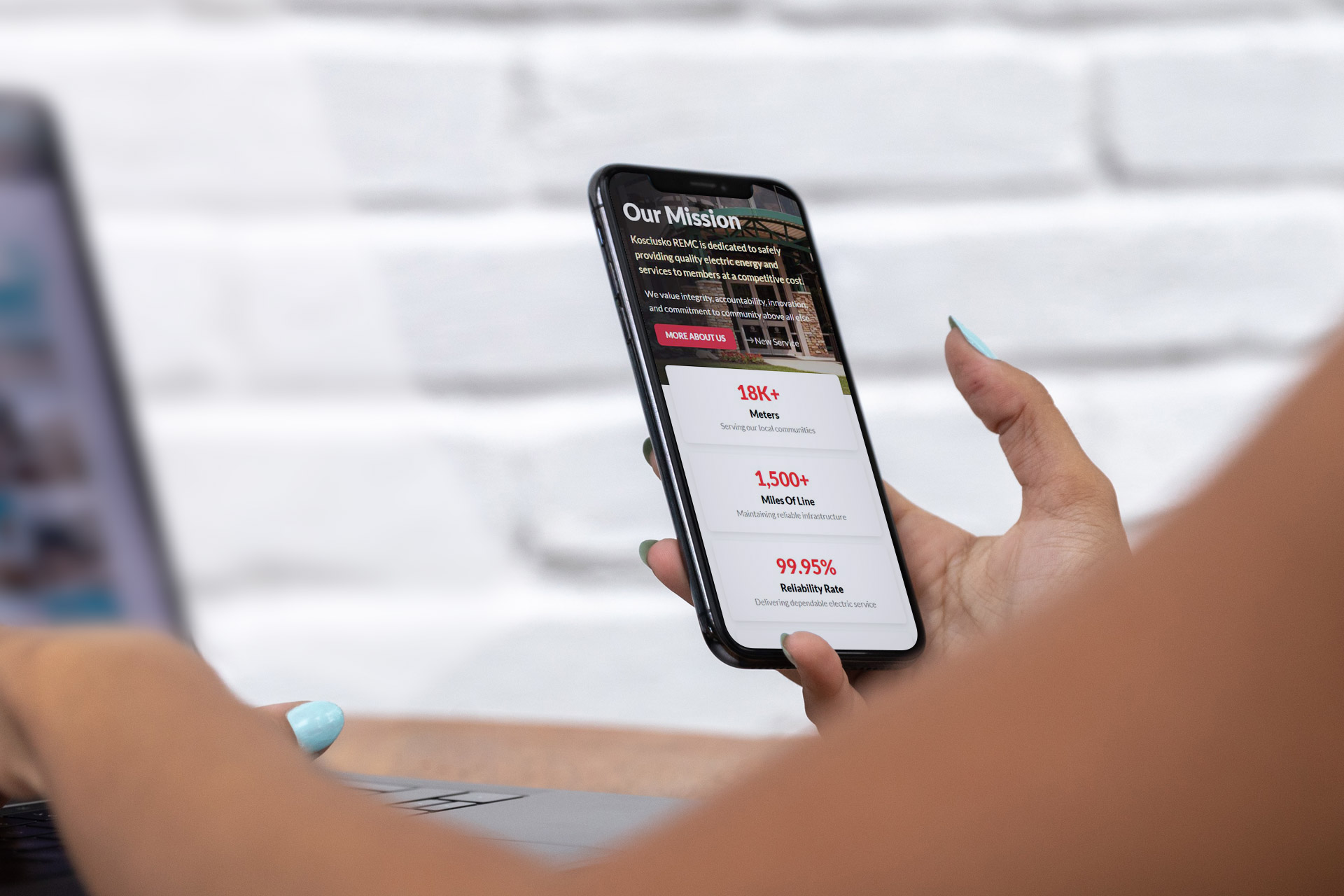 Person holding a smartphone displaying a website with statistics and mission statement.