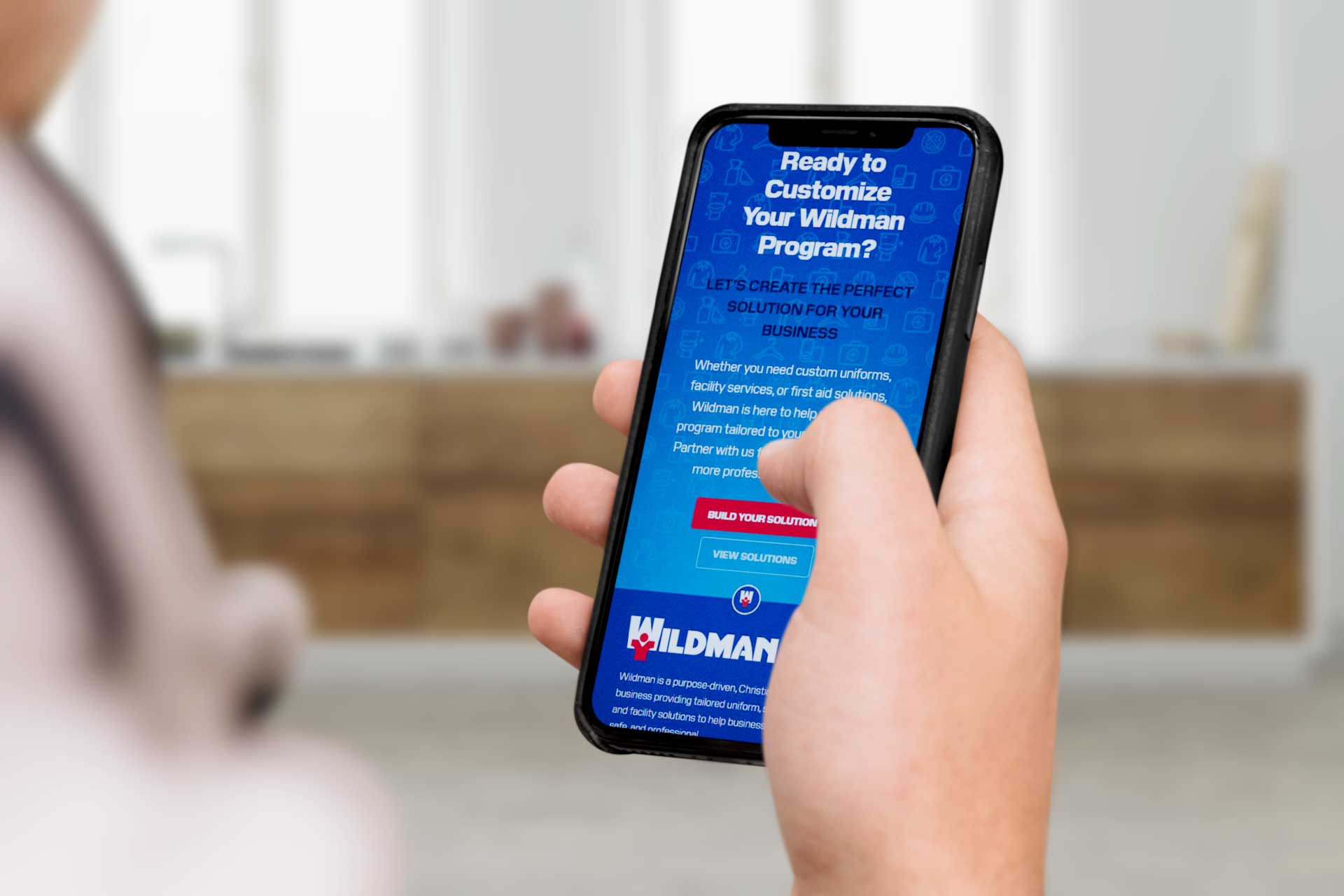 Person holding smartphone displaying a Wildman Program customization webpage.