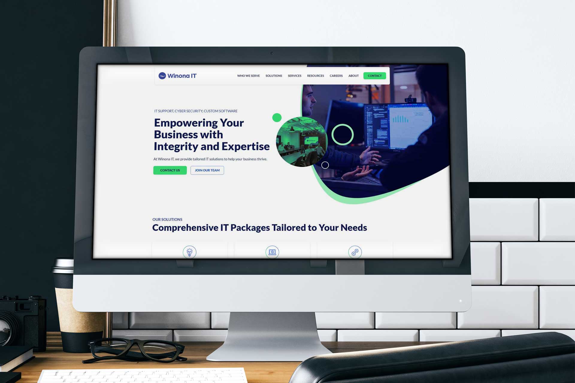 Computer monitor displaying a business IT services website in a modern office setting.