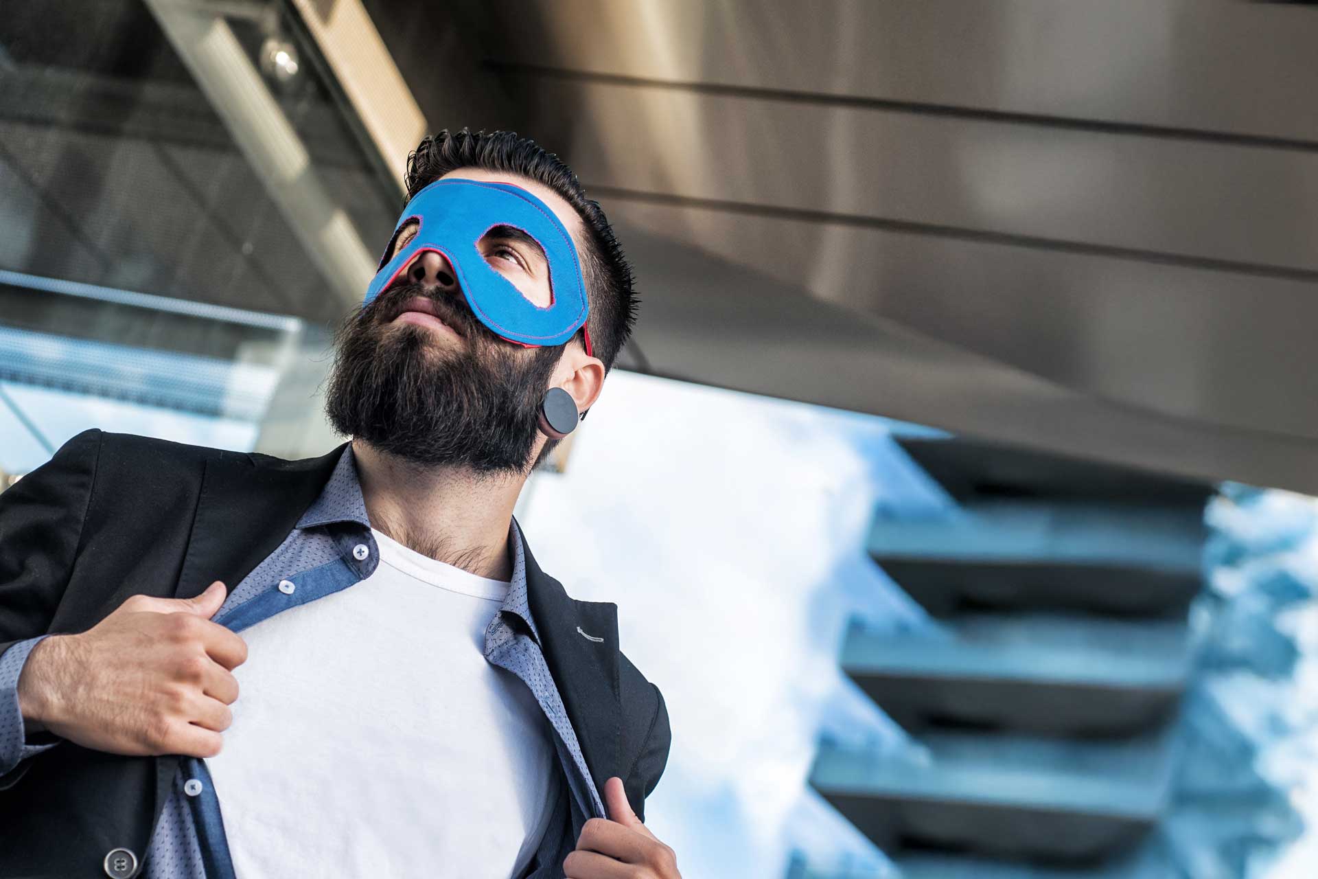 Man in a blue superhero mask gazes skyward by a modern web design firm.