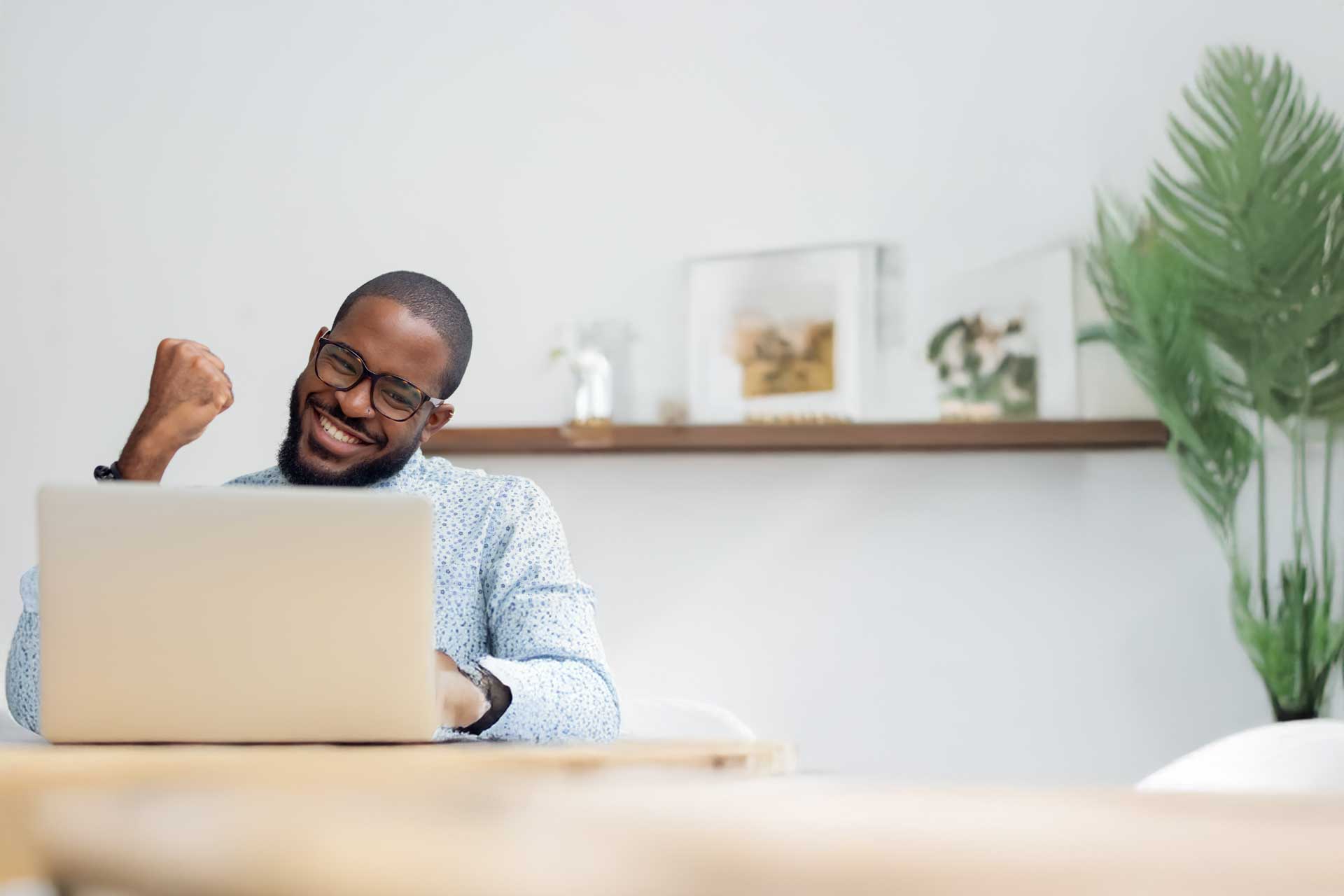 Person celebrating an email marketing win at a desk near a plant.