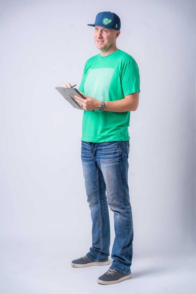 Man in a green shirt and jeans holding a web design contract against gray backdrop.