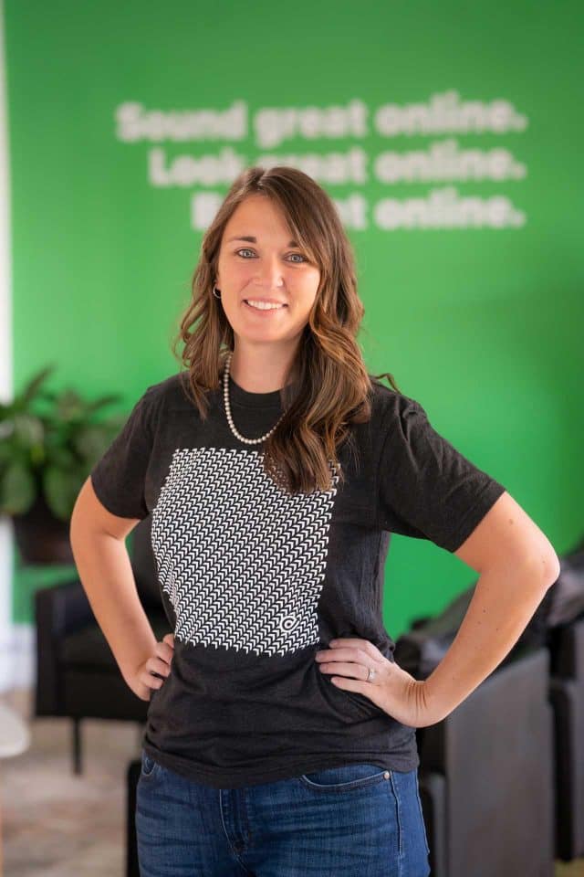 Person in black shirt, a brand consulting pro, stands by green wall with white text.