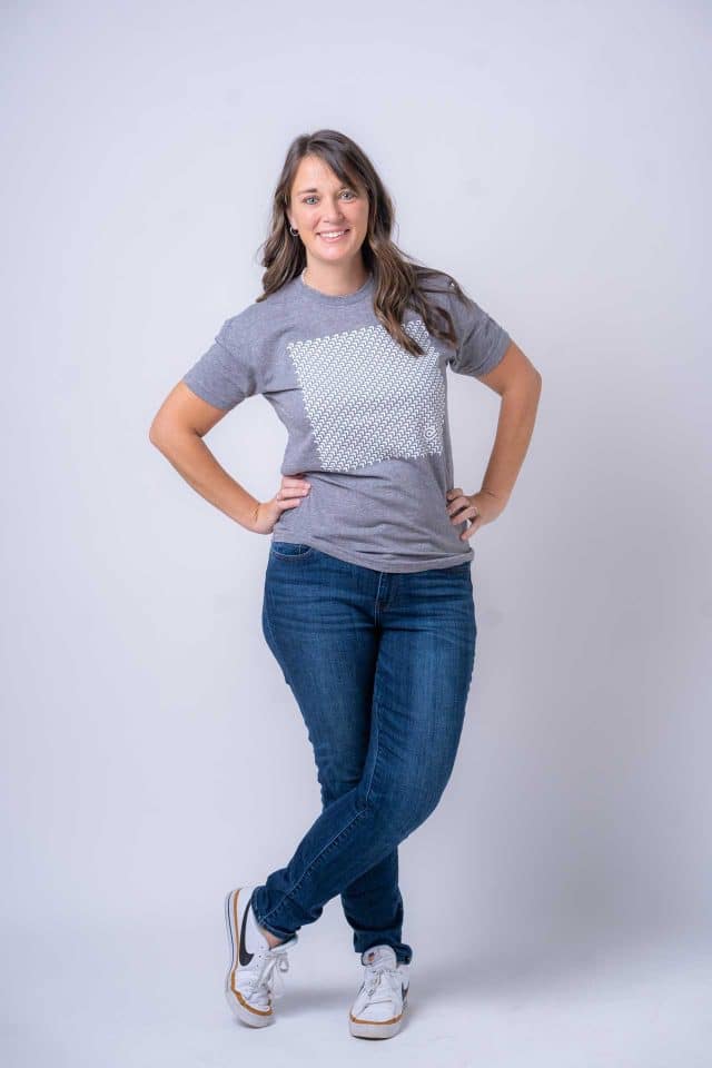 Person smiling in a gray t-shirt and jeans, poised like great online reviews.