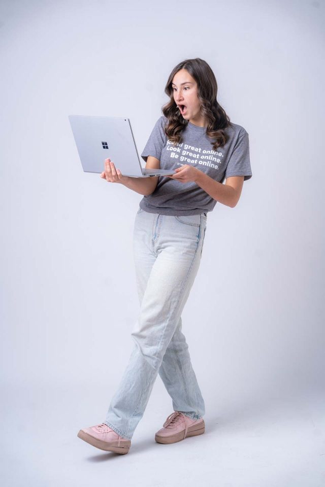 Person looking surprised at a laptop while standing.