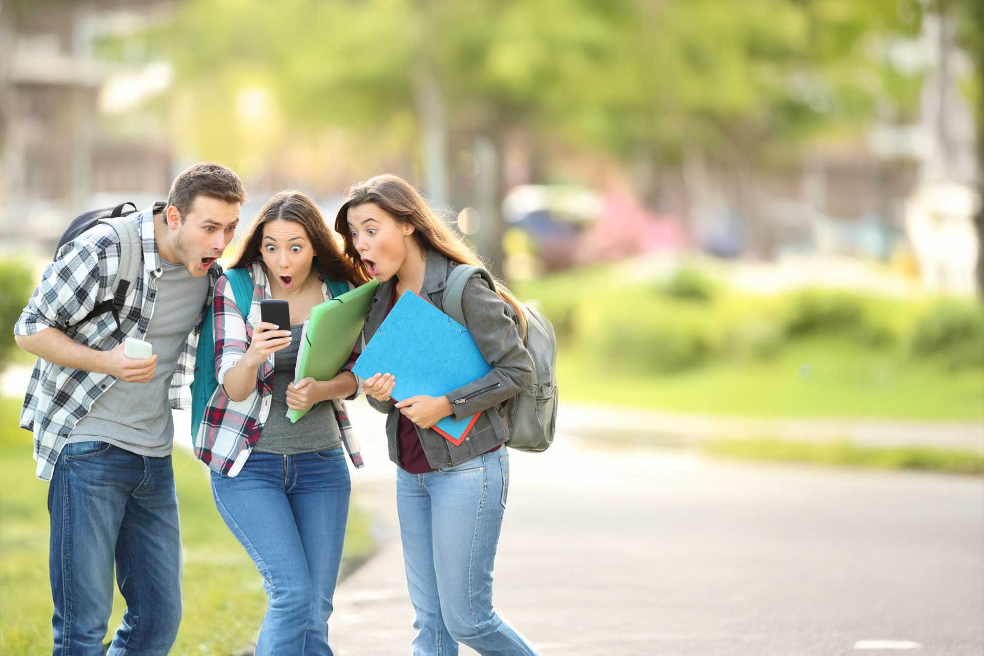 Three surprised people explore web design trends on a phone outdoors.