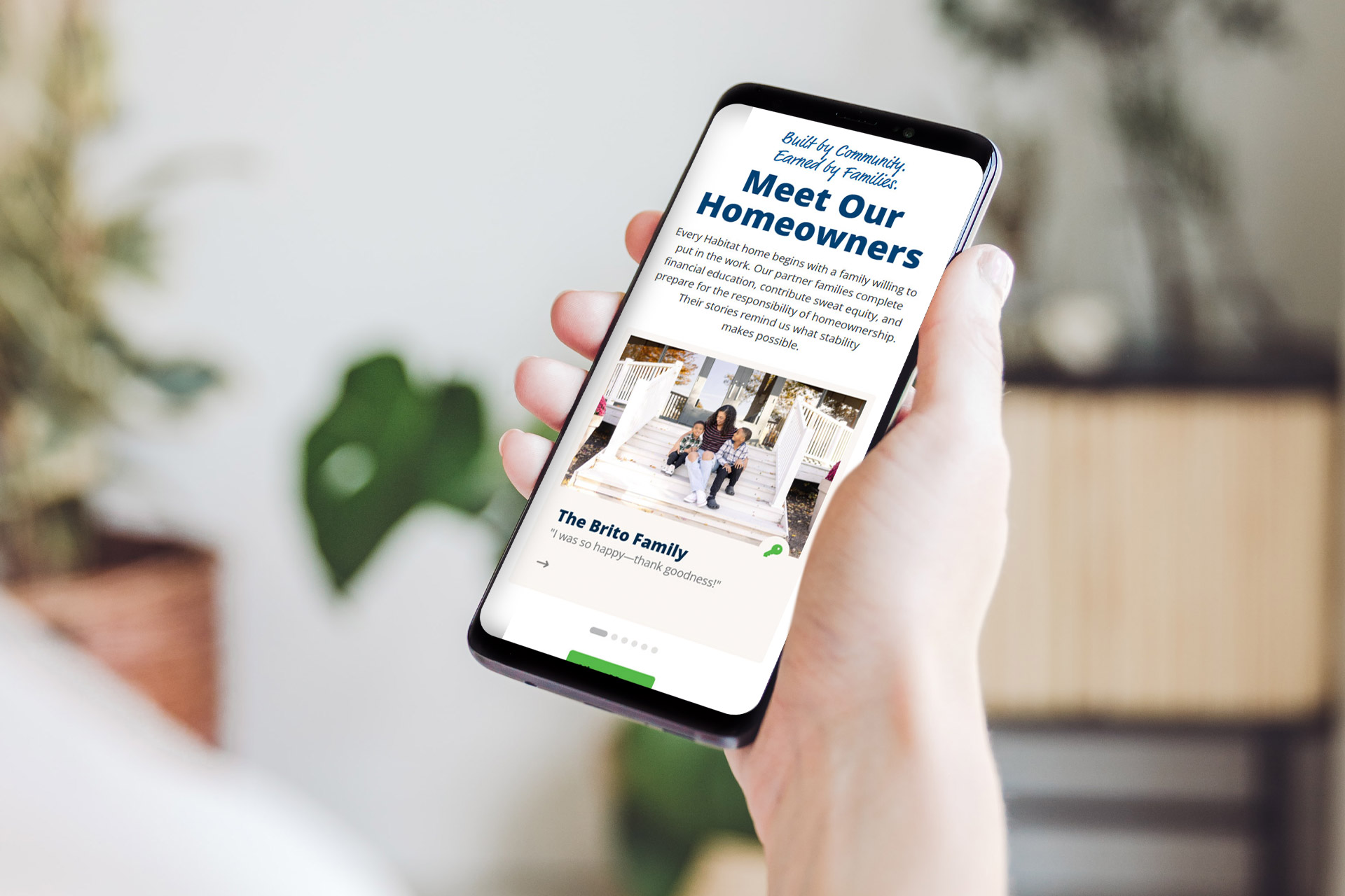 Person holding a smartphone displaying a Meet Our Homeowners webpage.