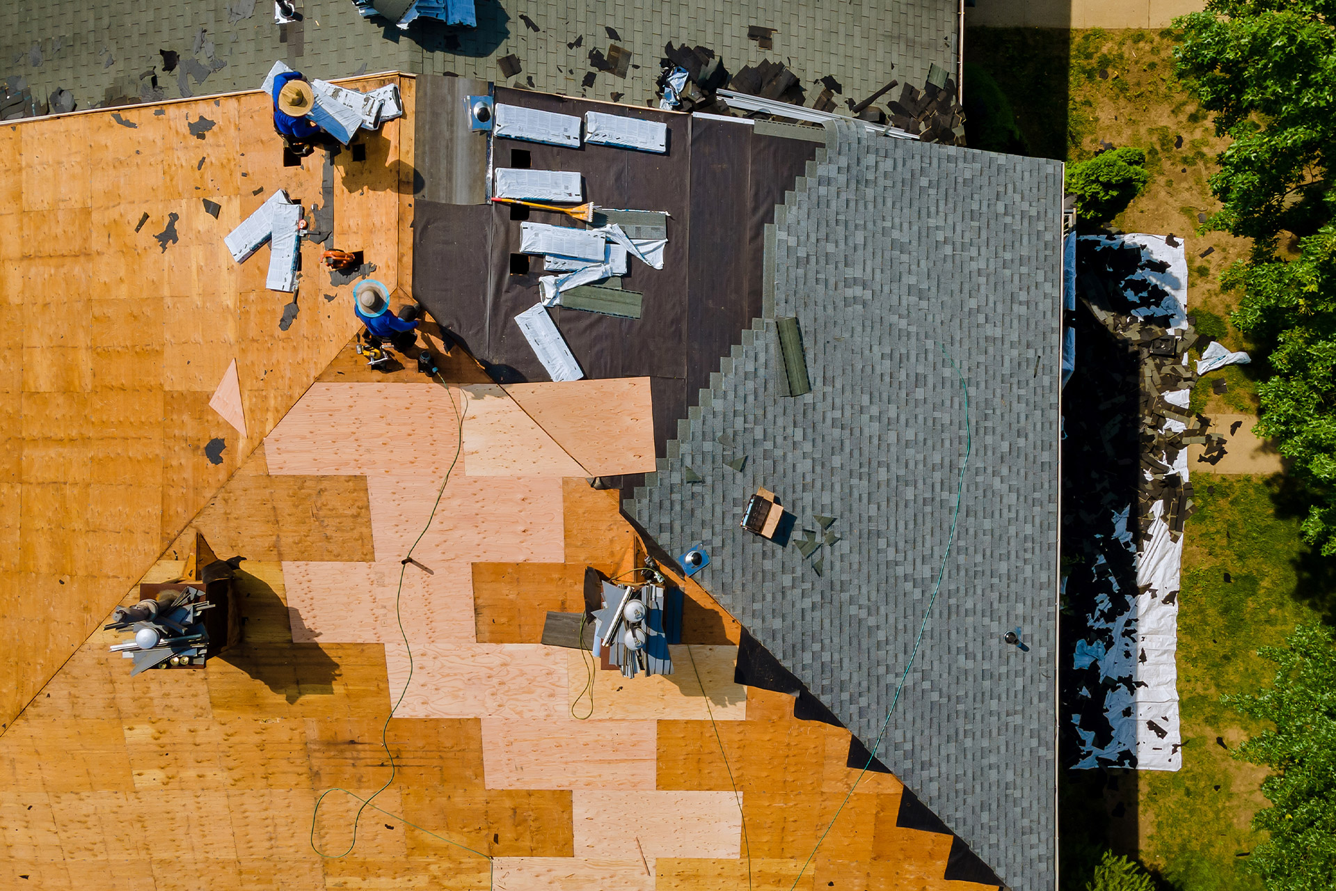 Aerial view of workers installing shingles on a house roof.