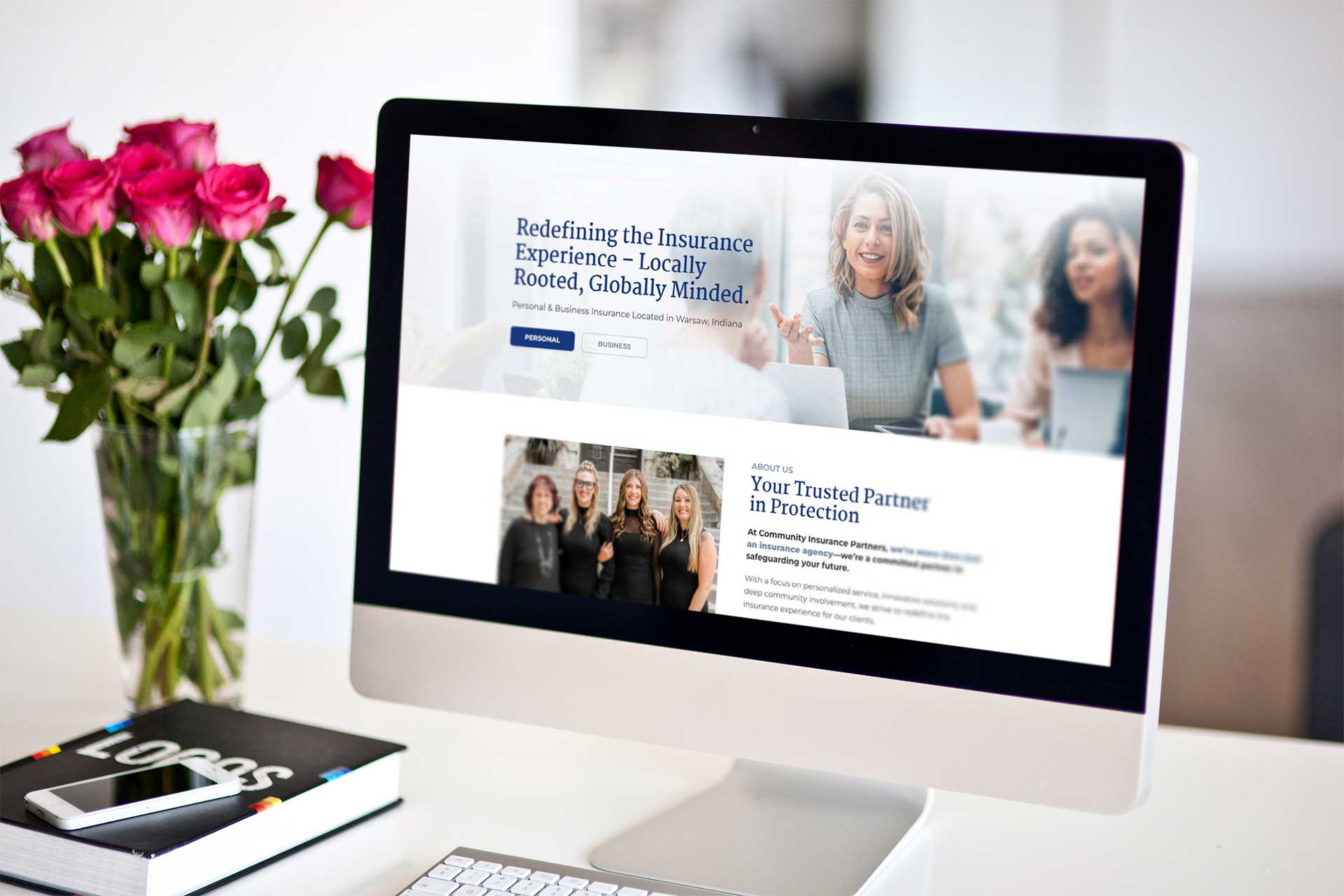 Community Insurance Partners website on screen, flowers nearby.