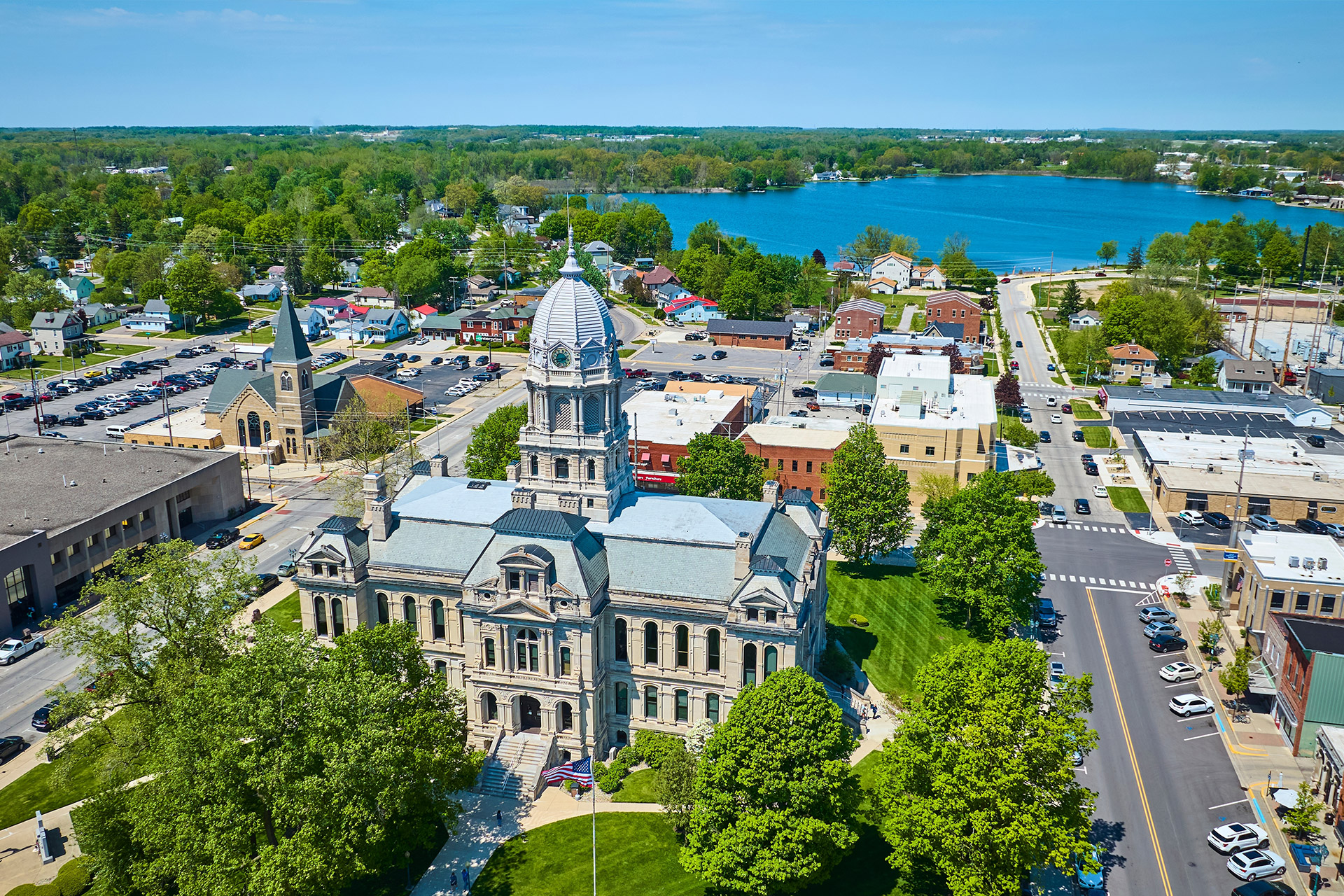 This image shows a courthouse, a church, and a lake in a small American town.