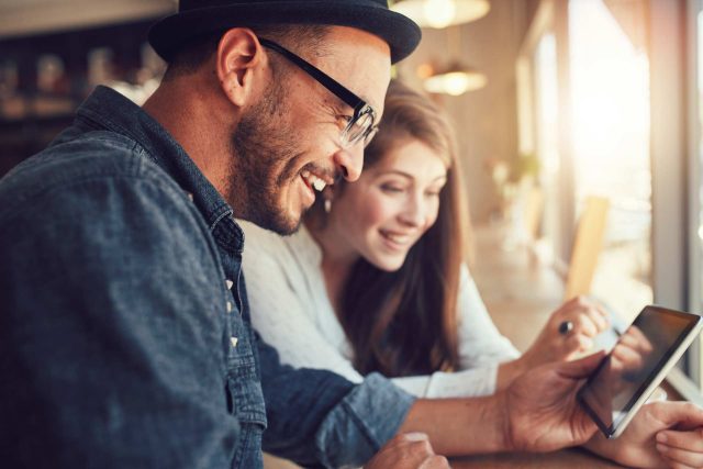 Two people smiling at a tablet in a bright room with Kosciusko Connect.