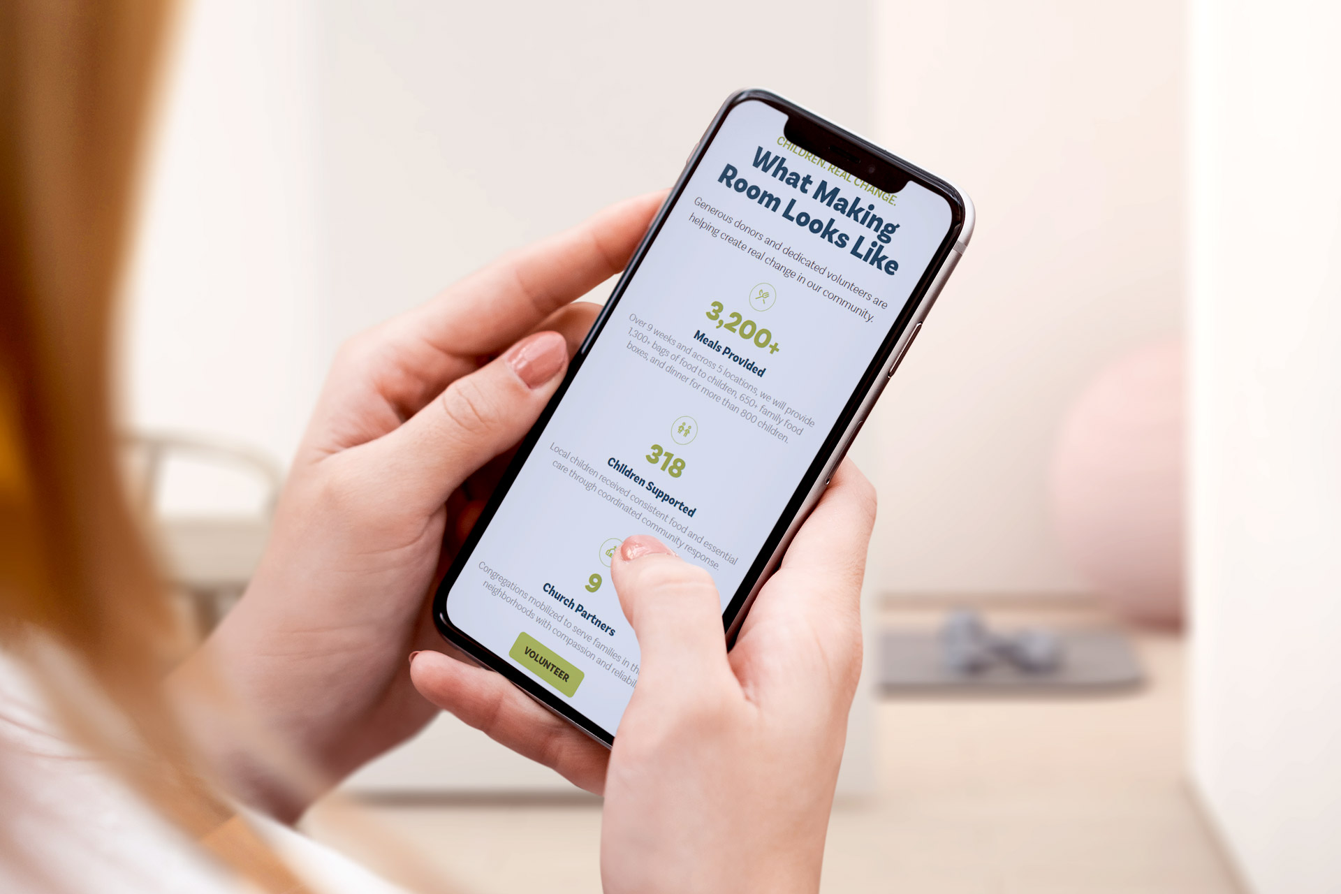 Person holding a smartphone reading a stats page with bold numbers and green text.