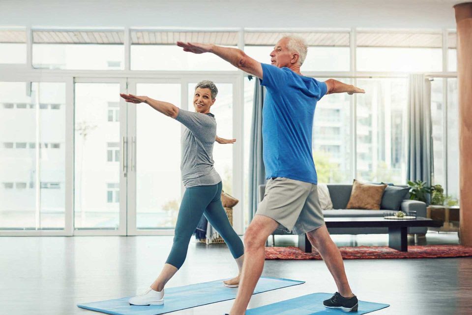 Two people doing yoga in the bright living room of Lake City Restoration.