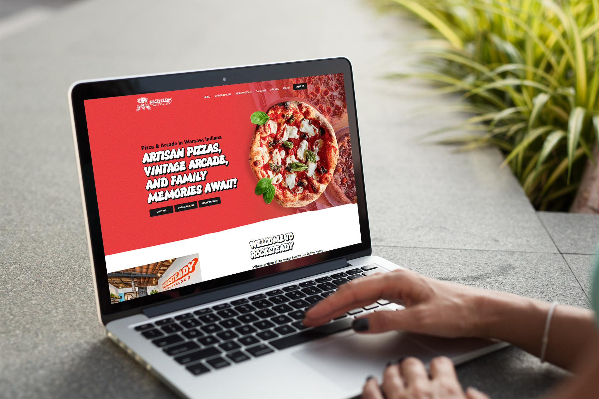 Person using a laptop displaying a pizza restaurants website on the screen.
