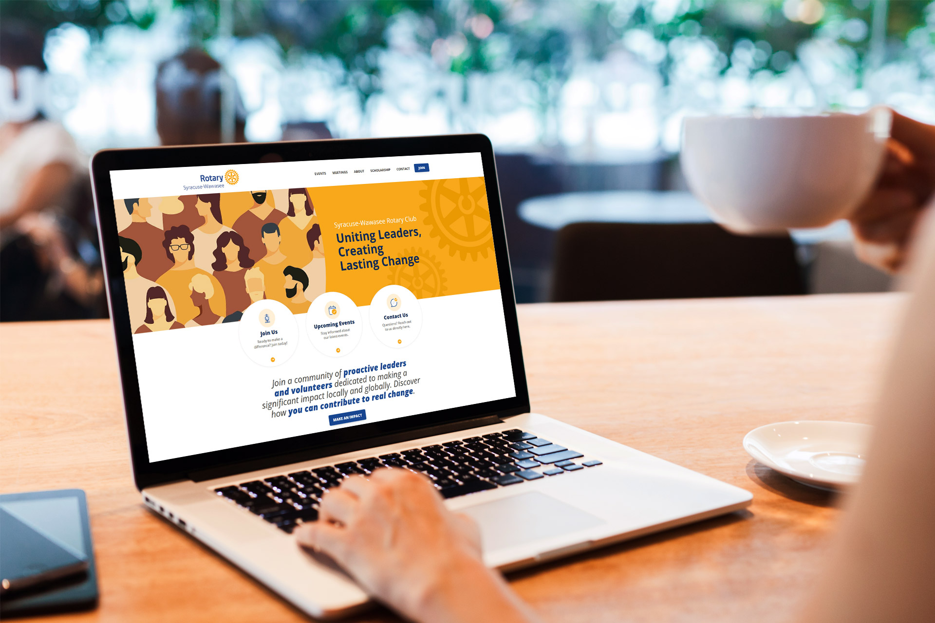 Person using a laptop at a table with a Rotary International webpage on the screen.