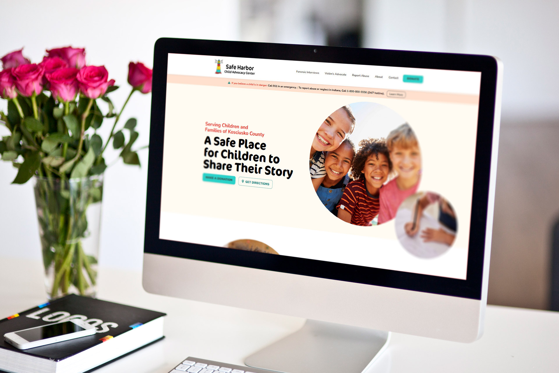 Computer screen displays a childrens advocacy website near a vase of pink roses.