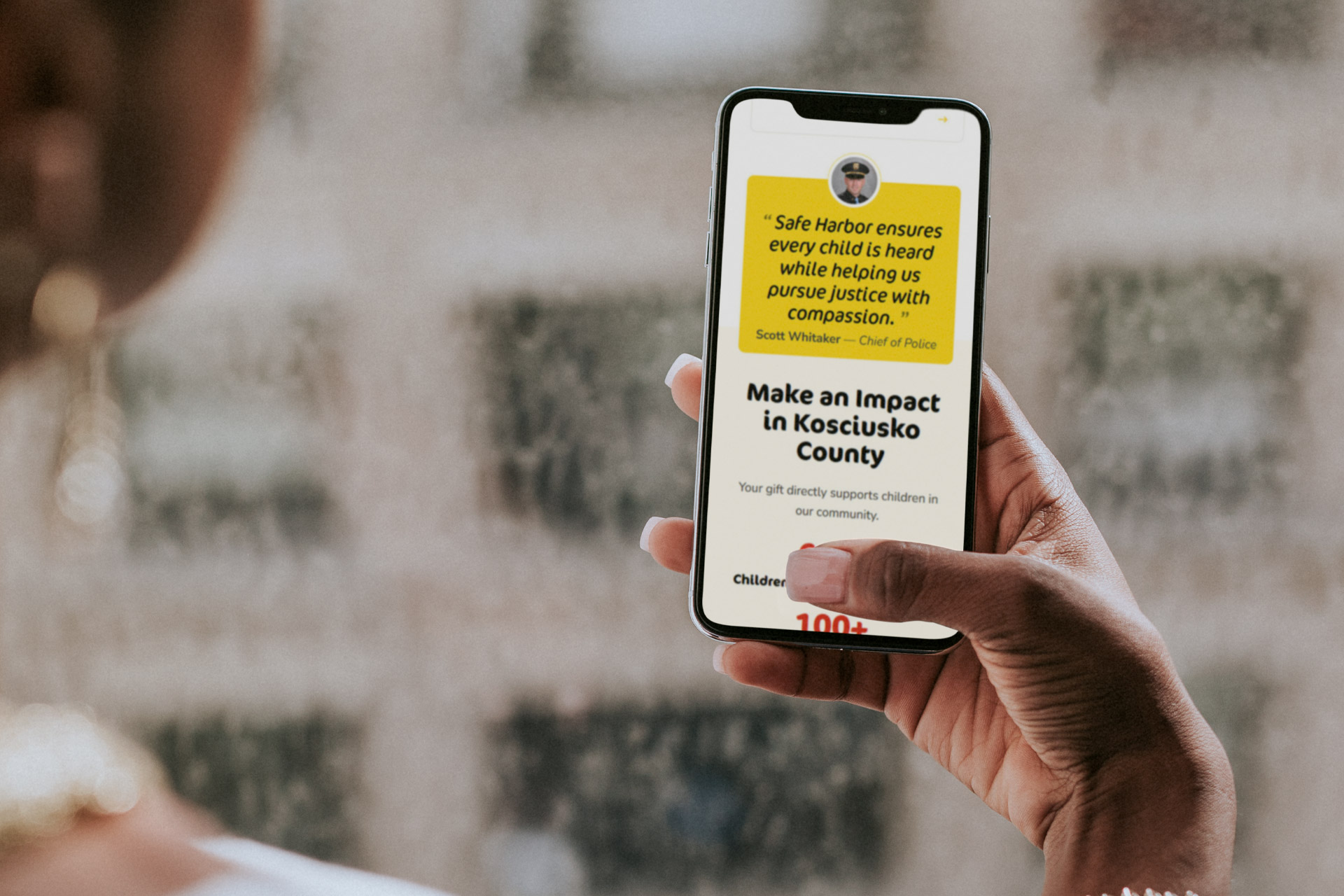 Person holding a smartphone displaying a charitable donation webpage.