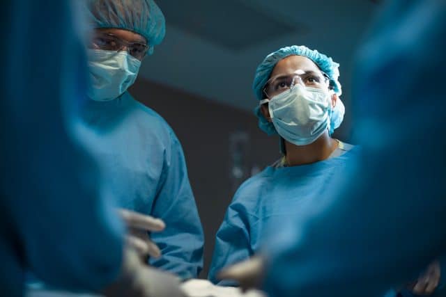 Surgeons in blue scrubs using BioPoly materials during a procedure.