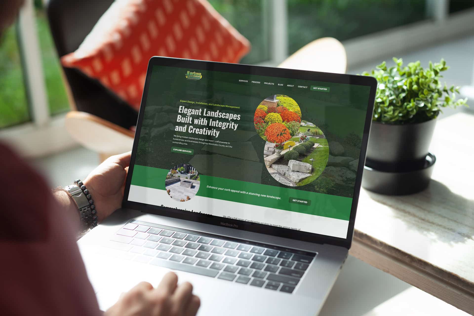 Person browsing Horizon Landscapes website on a laptop by a window.