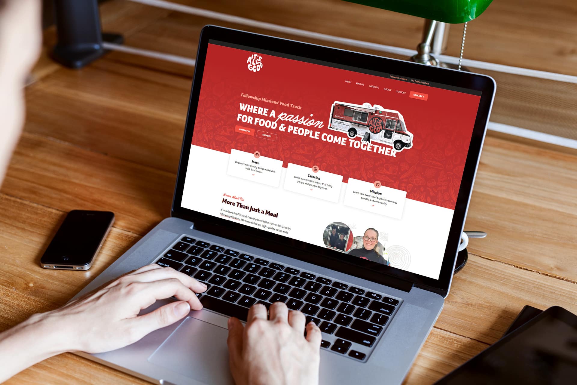 Person using a laptop to browse a food truck website on a wooden desk.