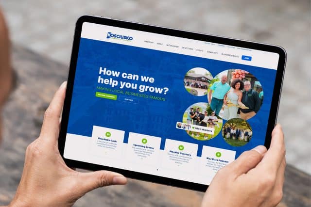 Person holding a tablet showing Kosciusko Chamber of Commerce website info.
