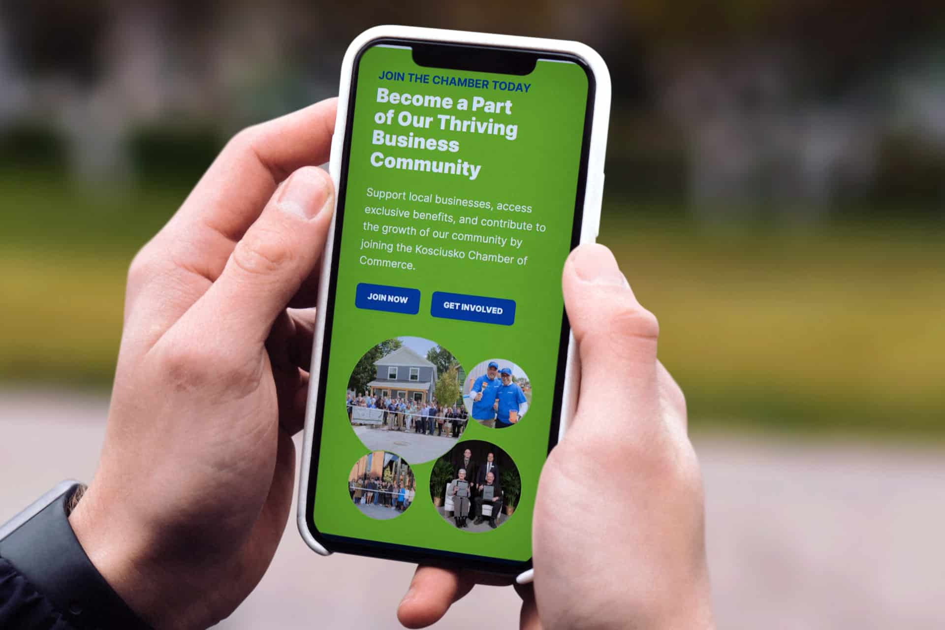 Hands holding a smartphone displaying the Kosciusko Chamber of Commerce webpage.
