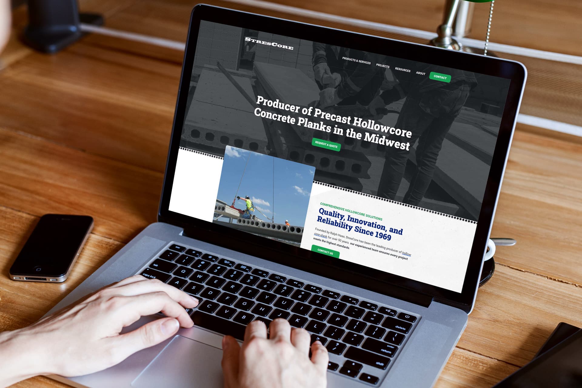 Laptop showing StresCores precast concrete website on a wooden desk.