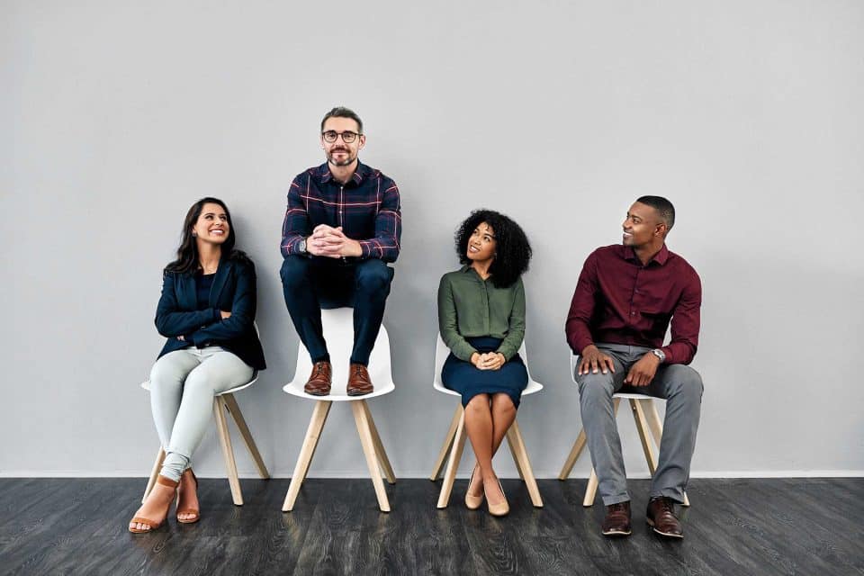 Four people seated, one perched above, exchanging social media marketing tips.