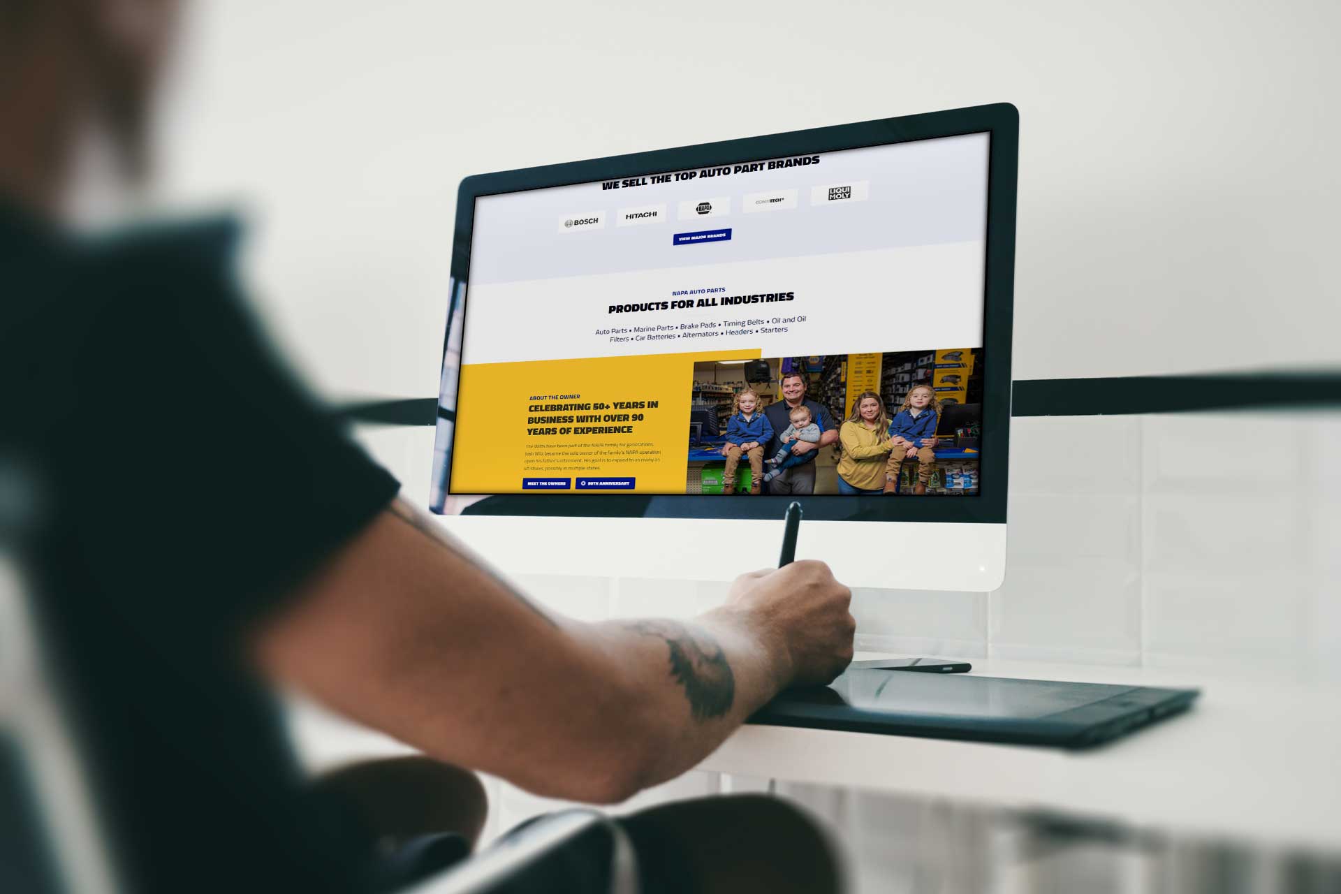 Person using a pen tablet at a desk with a large NAPA monitor screen.