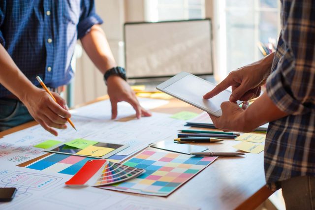 Two people discussing Blue Note Design plans and a color palette on a table.