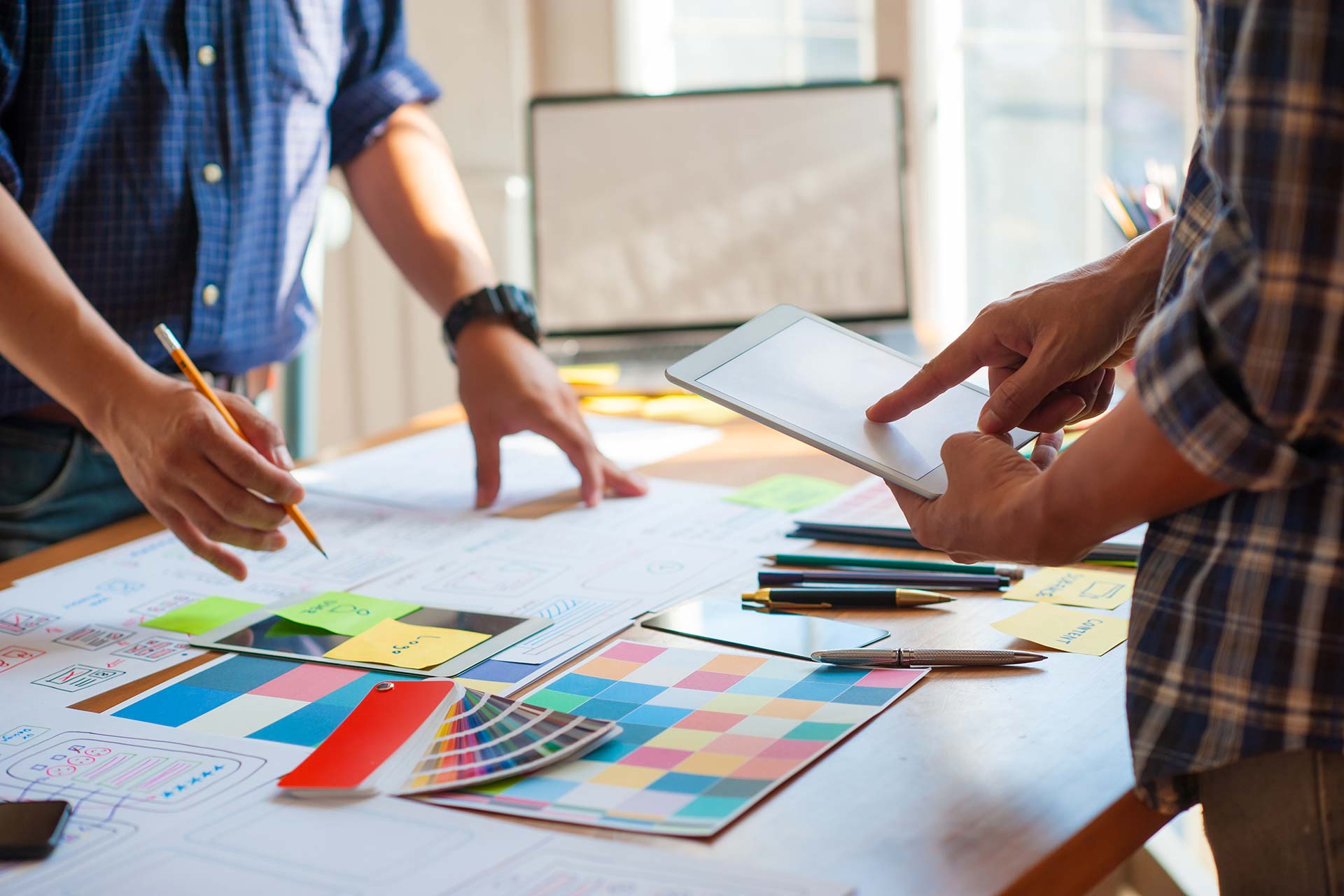 Two people discussing Blue Note Design plans and a color palette on a table.