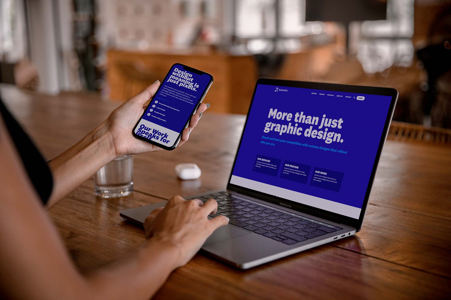 Person holding phone and using laptop with similar blue design screens.