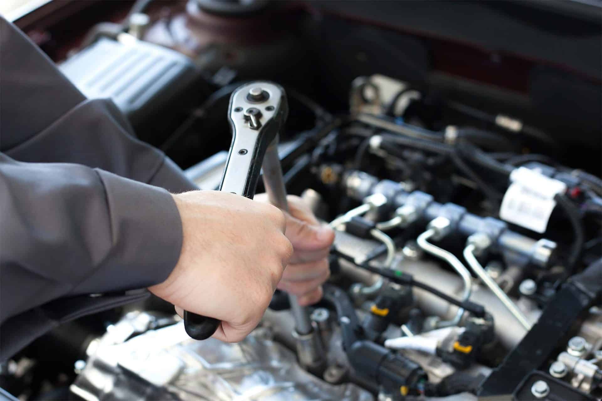 Hands using a wrench on a Boggs Automotive car engine.