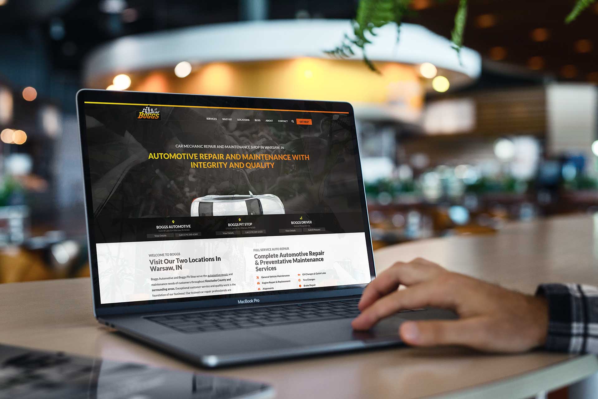 Person using a laptop displaying the Boggs Automotive repair website.
