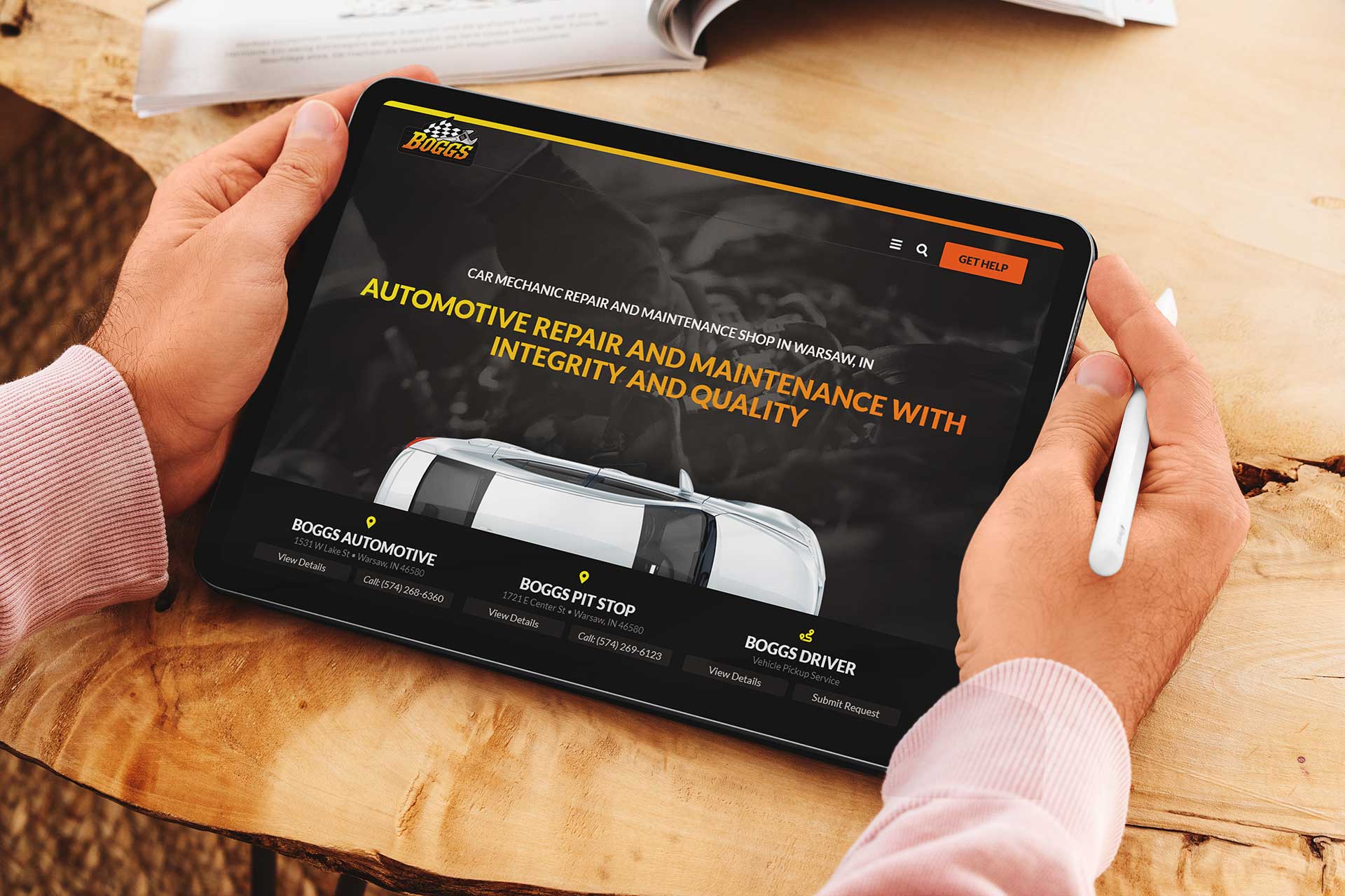 Person holding a tablet displaying Boggs Automotives repair website.