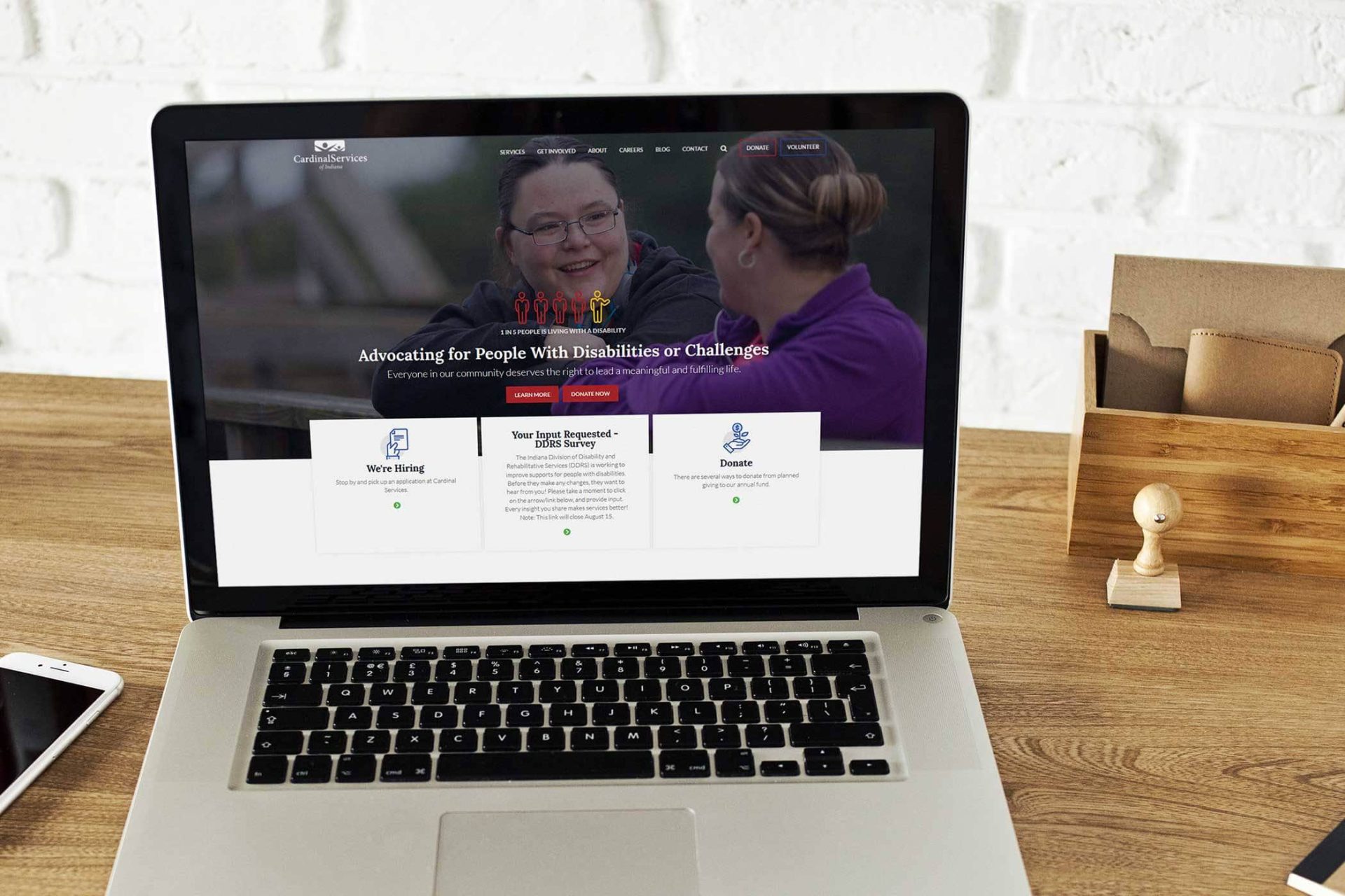 Laptop displaying a website for disability advocacy on a wooden desk.