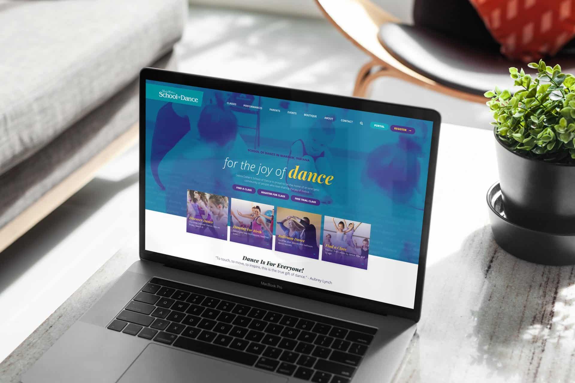 Laptop displaying Debra Colliers School of Dances website next to a plant.