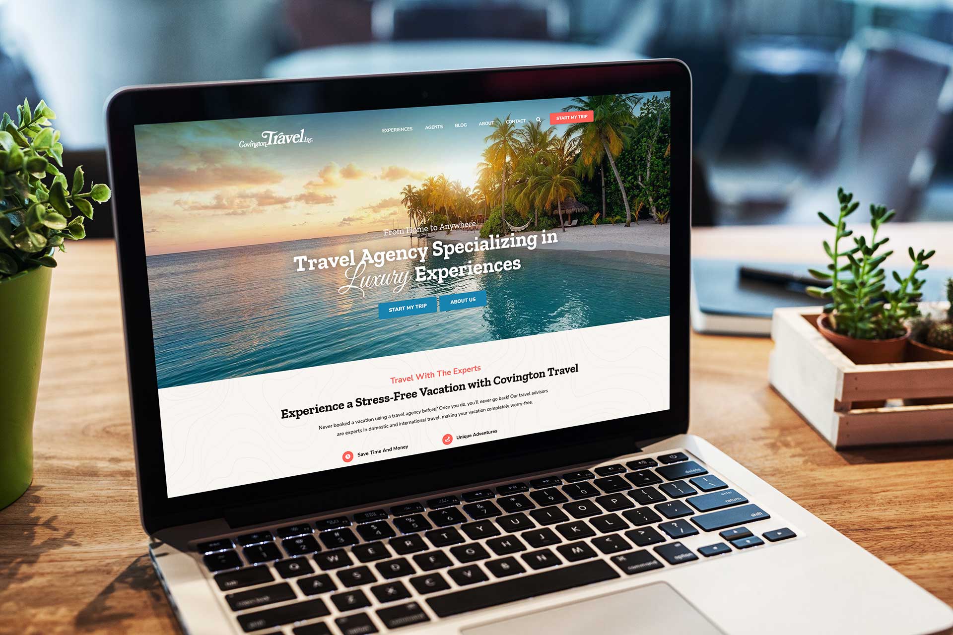 A laptop displays the Covington Travel site, sitting on a wooden desk with plants.